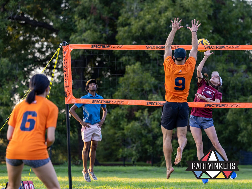 Employees playing outdoor volleyball during a corporate field day team-building activities.