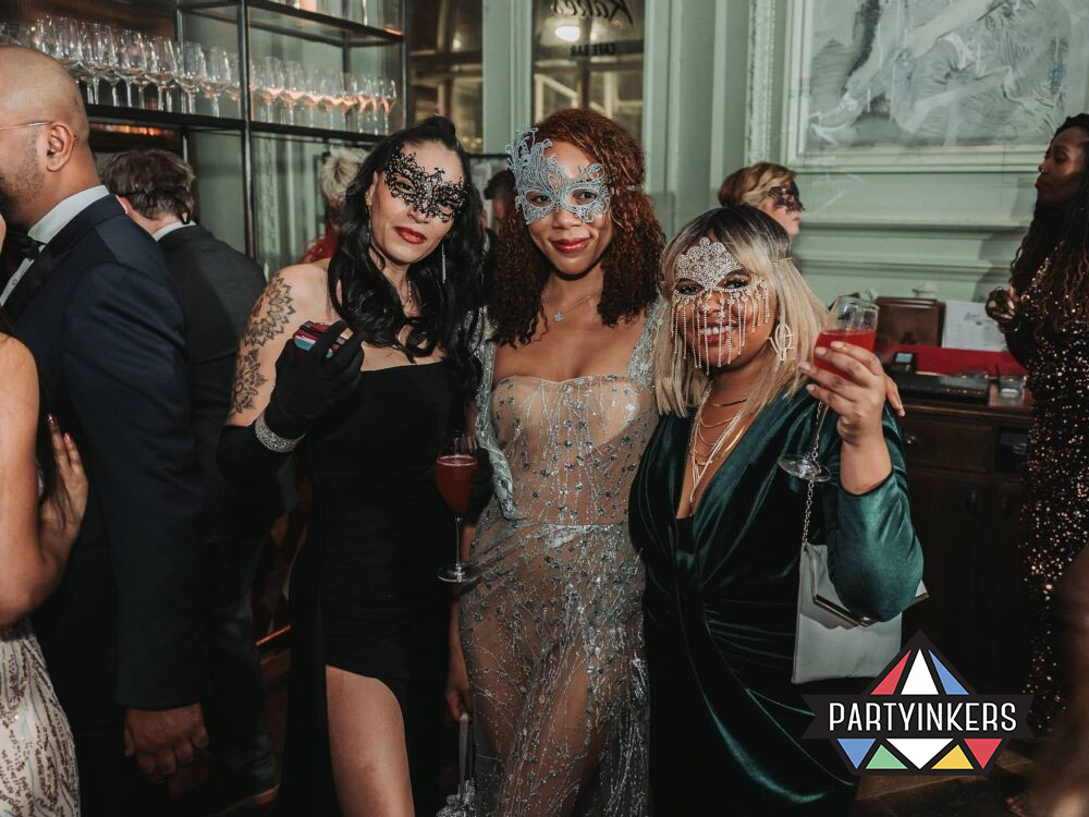 Guests in elegant masks enjoying drinks at a unique company event themes corporate event.