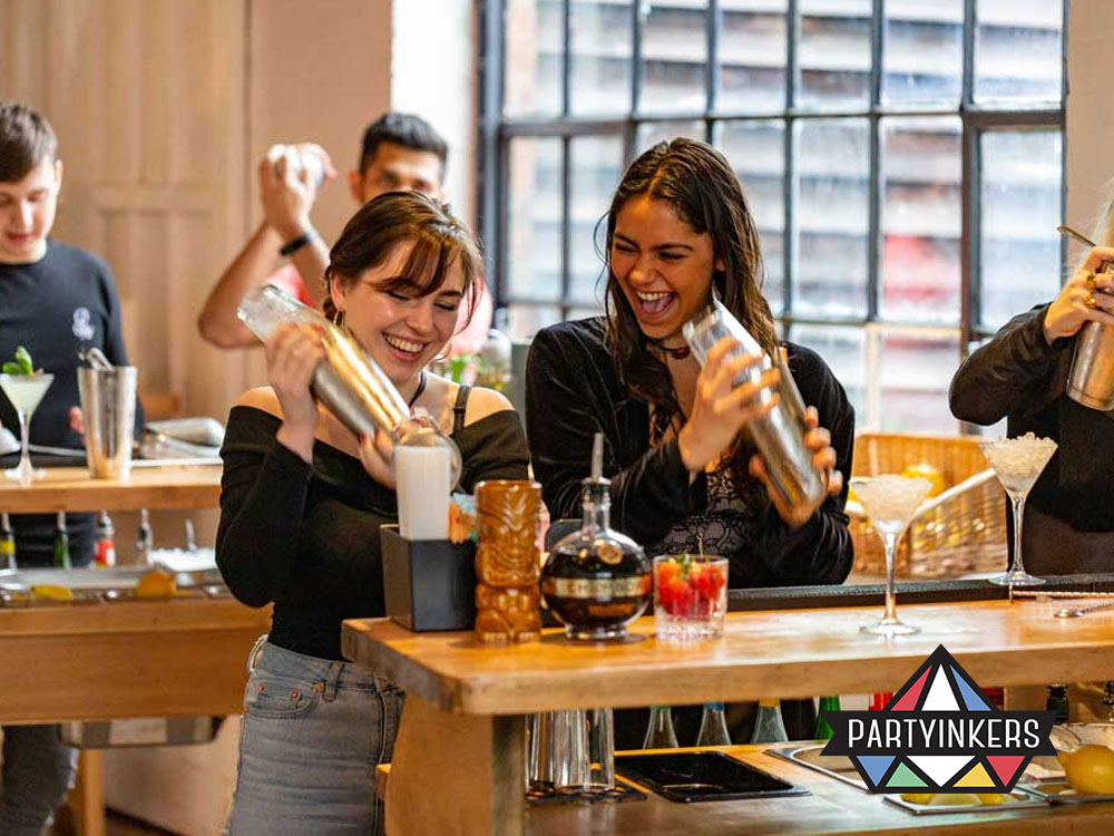 Employees laughing while learning to mix drinks during a fun corporate event idea.