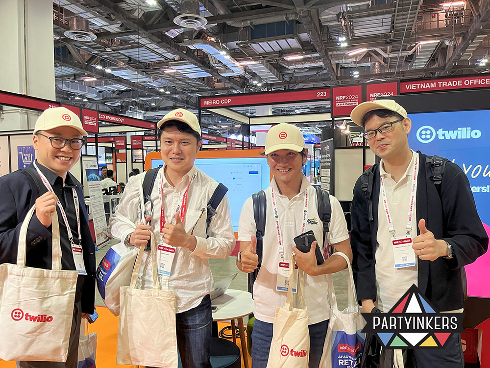 Twilio booth visitors showcasing branded tote bags, part of an experiential lead capture at trade shows activation powered by Partyinkers.